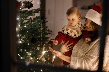 Happy family decorating christmas tree in magical eve. Merry Christmas and Happy Holidays! Mother...