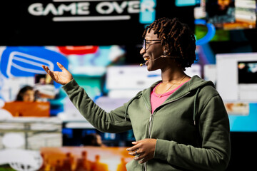 Cheerful public speaker doing presentation on social media trends, showing clips on screens. African american woman highlighting importance of online engagement and global connection during speech