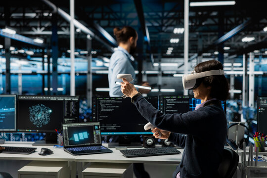 Data center technician monitoring AI systems using virtual reality, adjusting deep learning parameters. Server room IT expert wearing VR headset enhancing neural networks performance
