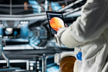 Close up of cosmonaut in orbital station running Mars data analysis on tablet. Spaceship crew member looking at galaxy visualization, doing Martian surface research to assist planetary exploration