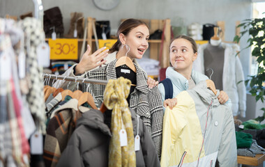 Adult woman and teenage girl choosing outerwear for autumn and winter in clothing store
