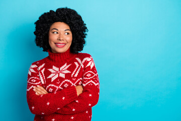Smiling woman in festive sweater with curly hair celebrates holiday season against vibrant blue...