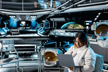 Female astronaut scientist operating spacecraft control interface using laptop. Woman researcher...