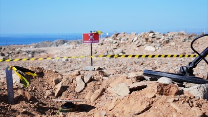 Demining experts using a metal detector and danger signs for humanitarian mine action, clearing land from anti-personnel mines, contributing to peace and post-conflict recovery