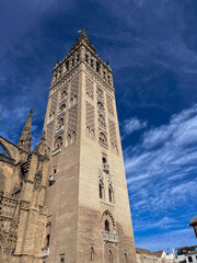Die Giralda in Sevilla unter blauem Himmel, ikonischer Glockenturm der Kathedrale mit maurischer Architektur und feinen Verzierungen, aufgenommen an einem klaren Sonnentag in Andalusien.