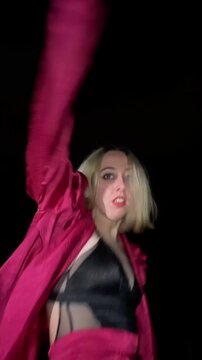 Young woman performing waacking dance at night