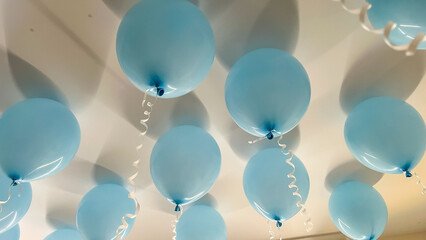 Blue balloons are suspended from the ceiling, creating a festive atmosphere for celebrations, with...