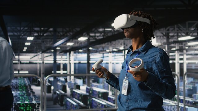 Data center programmer using virtual reality technology to simulate artificial intelligence neural networks. Woman in server farm using VR headset equipment to oversee AI systems,