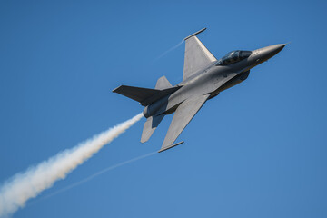 Fighter jet performing a high-speed maneuver in clear sky