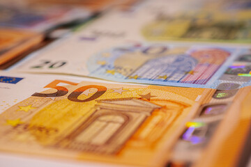 A detailed close-up view of various euro banknotes, including €20, €50, and €100...