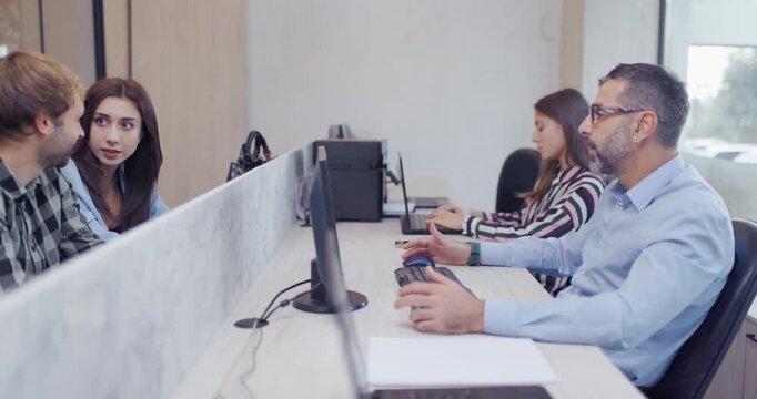 Couple Consults with a Travel Agent in a Tourist Agency to Plan and Book Their Vacation