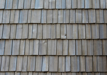Close-up of a wooden shingle roof texture showing natural grain and weathered wood pattern, ideal for backgrounds or design materials.