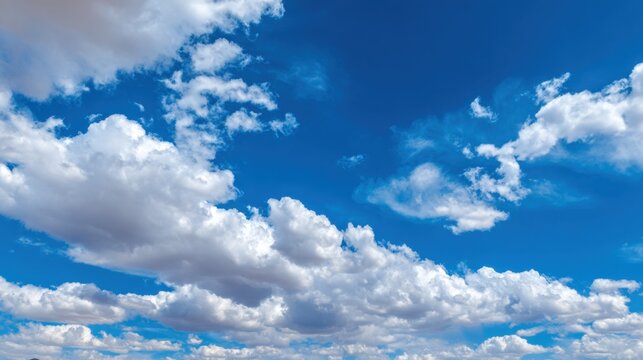 Fluffy clouds float in a clear blue sky creating a serene and uplifting atmosphere of peace.