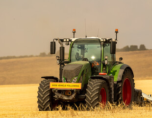 Fototapeta premium Modern tractor on a wheat field at harvest in the UK.