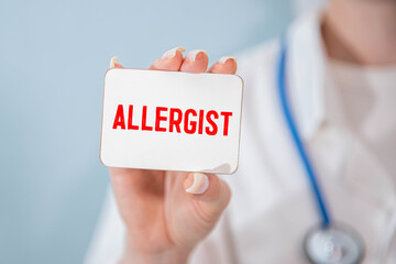 The doctor holds a card with the text ALLERGIST . Medical concept. the medicine.