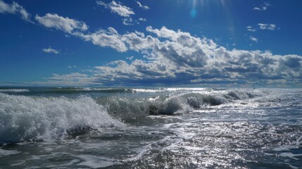 Fototapeta premium Bright sunlight sparkles on the ocean waves as they crash softly on the shore creating a calm scene.