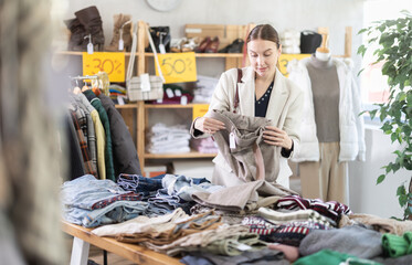 Glad young woman looking for pantaloons for cold season during sell-out in retail outlet
