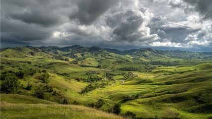 Obraz premium A sweeping view of green hills and valleys unfolds beneath an overcast sky filled with dramatic clouds.