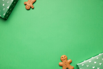 Gingerbread cookies placed on vibrant green background with decorative gift boxes, creating a festive atmosphere perfect for holiday celebrations and seasonal joy copy space