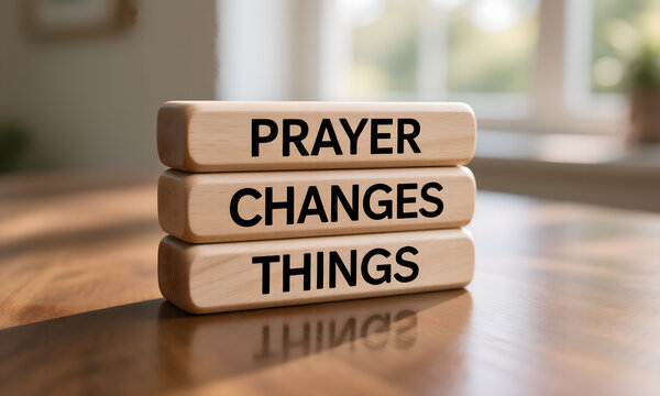 Inspirational message 'Prayer Changes Things' on stacked wooden blocks on a warm reflective table.