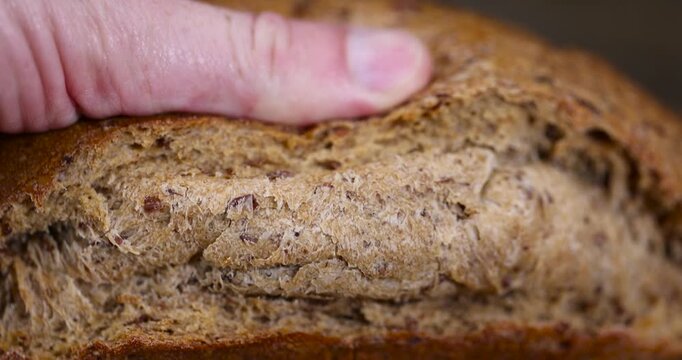 loaf of rye flour bread lies on the table on a cutting board, a small elongated loaf of freshly baked rye bread on an old cutting board for slicing bread