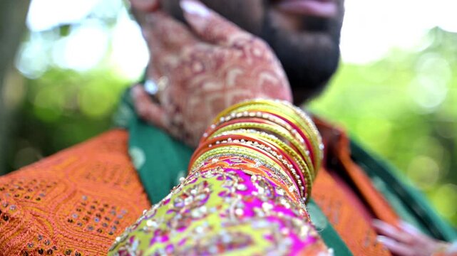 Close up view of Traditional Indian or Pakistan henna painted bridal hands patting a groom face. 