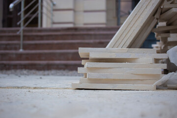 Obraz premium Large slabs of natural marble stacked at a renovation site against the backdrop of a porch under construction, close-up, the background is blurred with a bokeh effect
