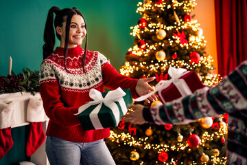 Festive scene of gift exchange by a Christmas tree in a cozy holiday-decorated living room with...