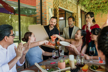 large group of friends or multi generation family eating pizza and having a dinner in a terrace party in Mexico Latin America, hispanic diverse and multicultural people in a restaurant