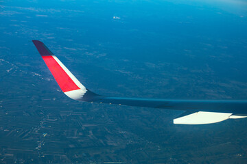Airplane wing against the vast expanse of landscape below. Wing of an airplane, a view from the plane window