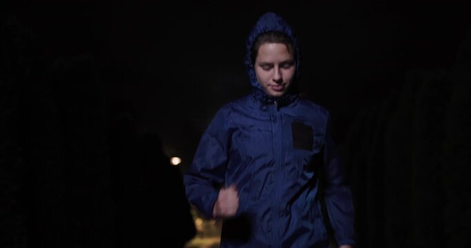 Portrait of a determined runner wearing a blue jacket at night, with serene expression and focused determination, portraying the spirit of night running and outdoor fitness during challenging
