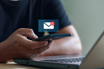 Businessman using smartphone and laptop with new email notification icon, representing online communication, digital messaging, mobile technology and internet connection in modern lifestyle.