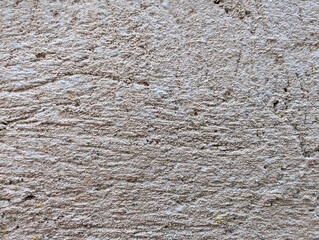 Close-up of rough grey sand and cement or concrete mix texture for exterior wall coating, plastering, construction and masonry background. Weathered coarse grainy surface with holes, irregular relief.