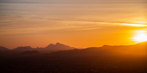Obraz premium Orange clouds silhouette mountain peaks In Sonora mexico during the dramatic beauty of a sunset or sunrise landscape