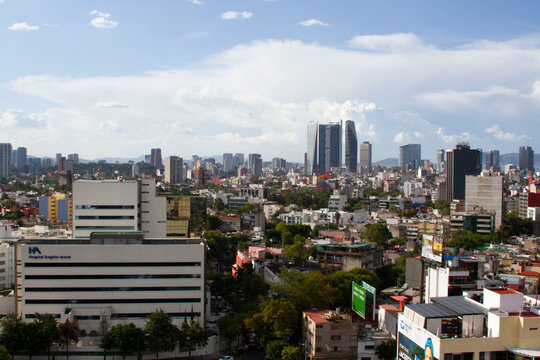 Edificios de la ciudad de M&eacute;xico en una tarde de verano con un cielo azul y nubes blancas