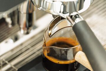 Coffee machine brewing espresso in to glass cup.Barista while preparing and working with coffee machine and making espresso coffee from arabica coffee beans.