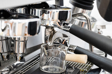Coffee machine brewing espresso in to glass cup.Barista while preparing and working with coffee machine and making espresso coffee from arabica coffee beans.