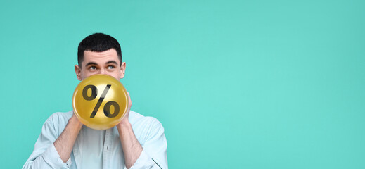 Man blowing golden balloon with percent sign on turquoise background. Discount offer