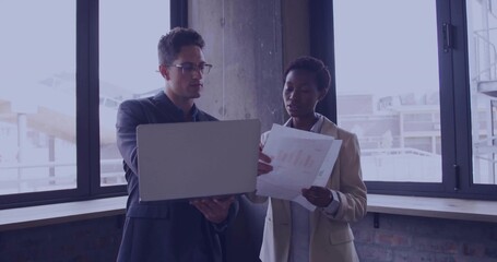Fototapeta premium Reviewing data, man in suit and woman in blazer at contemporary office, with laptop, chart sheet