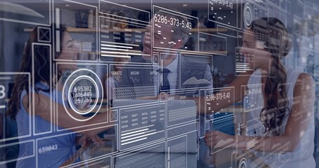 Analyzing team in business attire interpreting graphs, data in open office with transparent display