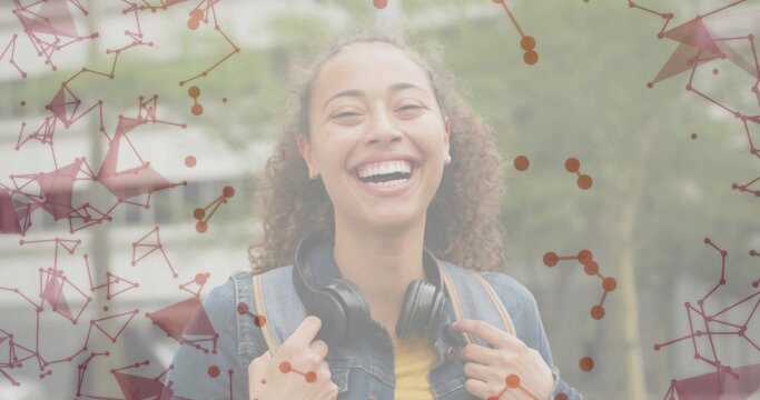 Smiling woman holding backpack walking on path in denim jacket, headphones under network overlay