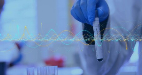 Raising gloved hand holding biohazard sample tube at lab bench, with tube rack and waveform overlay