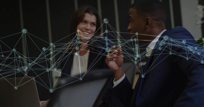 Discussing data Black man and white woman in suits at conference table with laptop, network overlay - Powered by Adobe