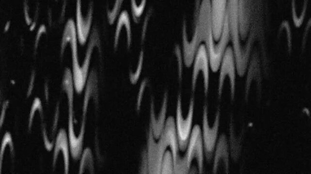 An abstract, monochromatic, wave-like pattern, creating a sense of dynamic movement and visual interest. The pattern is characterized by its curved, flowing lines