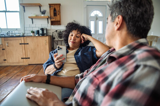 Mature couple sitting on a couch and using a phone at home