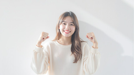 白背景に笑顔でガッツポーズをする若いアジア人女性