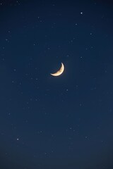 A sliver of waxing crescent moon illuminates the vast, inky blackness of the night sky, glow, nocturnal