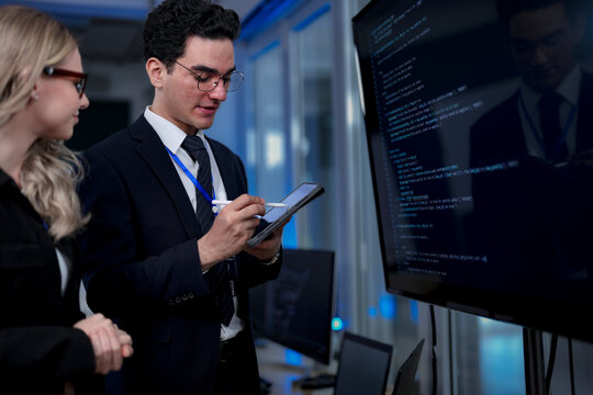 A quantum computing scientist explains a complex algorithm to a colleague, pointing to the code that will run on a quantum processor to solve a problem previously thought impossible.