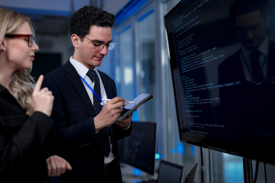 A quantum computing scientist explains a complex algorithm to a colleague, pointing to the code that will run on a quantum processor to solve a problem previously thought impossible.