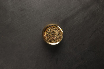 dry green fenugreek leaves powder in a brass metal pot on a dark surface with a clean and neat appearance striking contrast vibrant spice